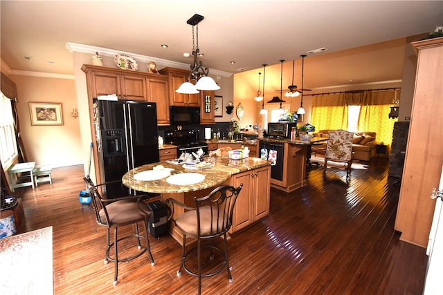 kitchen featuring ornamental molding, dark hardwood / wood-style floors, light stone counters, black appliances, and a kitchen island