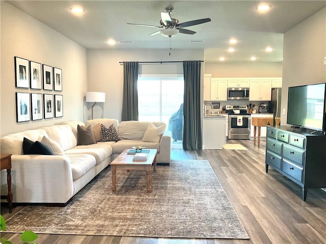 living room featuring sink, ceiling fan, and light wood-type flooring