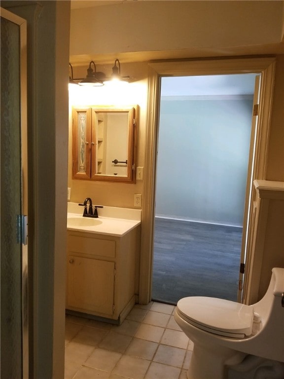 half bath with toilet, tile patterned flooring, and vanity