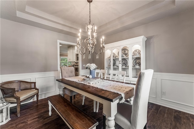 dining room with a tray ceiling, a notable chandelier, wood finished floors, and wainscoting