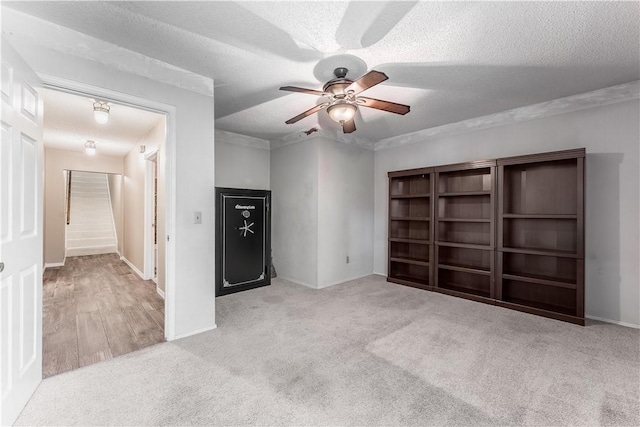 unfurnished living room featuring a textured ceiling, stairway, carpet, baseboards, and ceiling fan