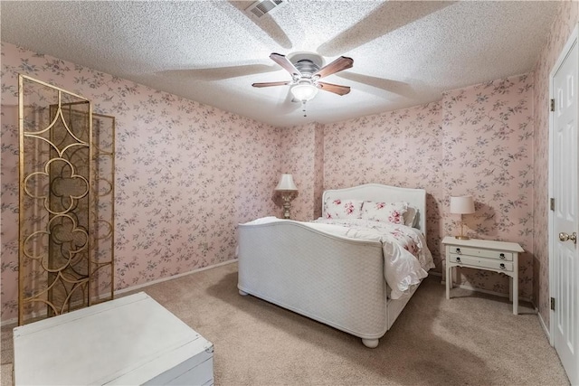 bedroom featuring visible vents, wallpapered walls, ceiling fan, carpet, and a textured ceiling