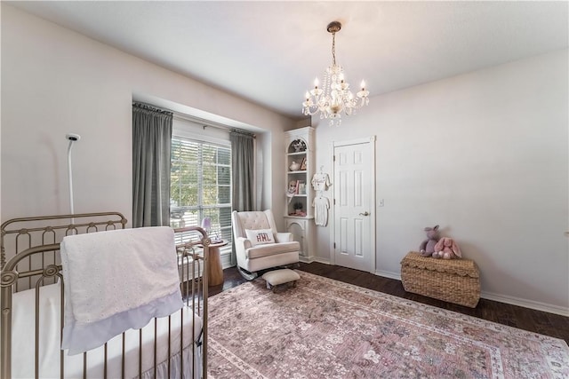 bedroom with baseboards, an inviting chandelier, and wood finished floors