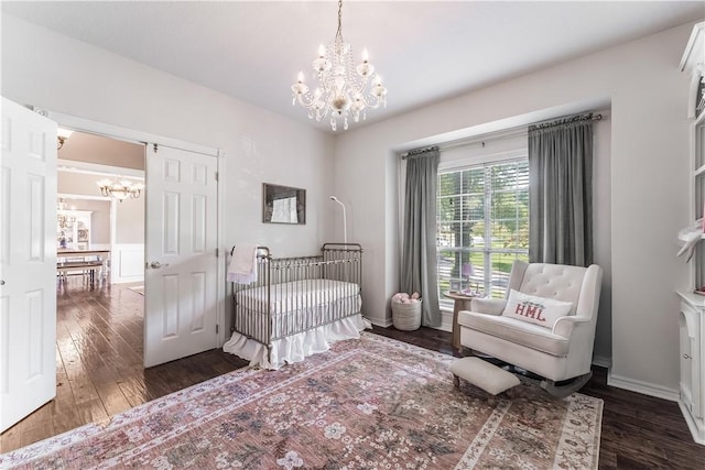 bedroom featuring a chandelier, a crib, and wood finished floors