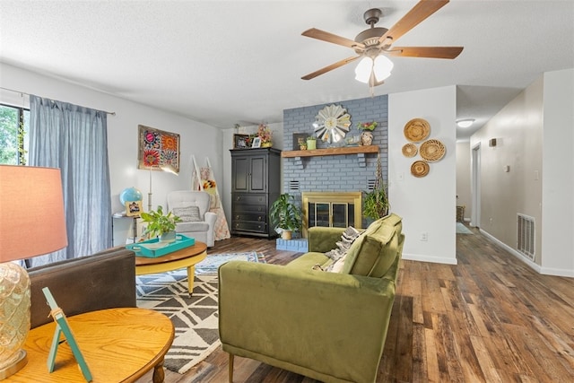 living room with a textured ceiling, ceiling fan, hardwood / wood-style floors, and a brick fireplace