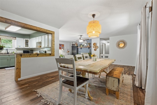 dining area featuring hardwood / wood-style flooring, a textured ceiling, sink, and ceiling fan