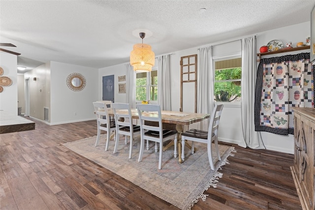 dining area with a wealth of natural light, a textured ceiling, and hardwood / wood-style floors