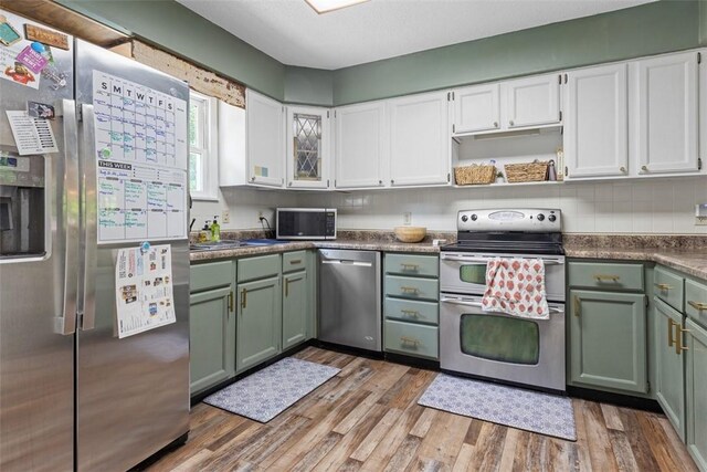 kitchen with light wood-type flooring, stainless steel appliances, green cabinets, and white cabinetry