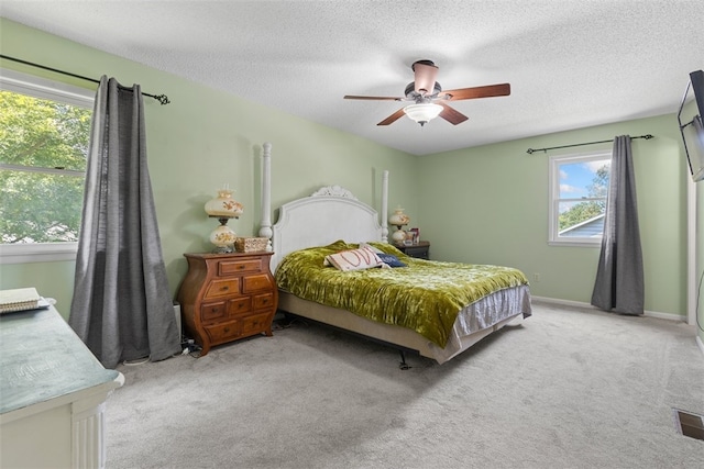 carpeted bedroom with ceiling fan and a textured ceiling