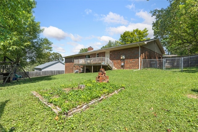 back of house with a wooden deck, a playground, and a yard