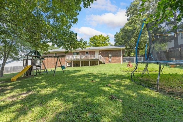 view of yard featuring a trampoline, a wooden deck, and a playground