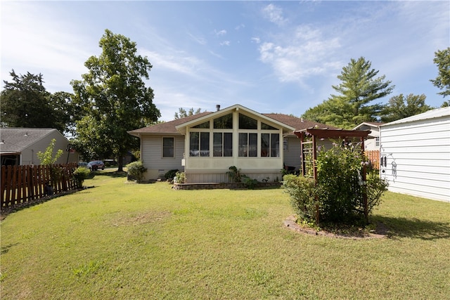 back of property with a sunroom and a lawn