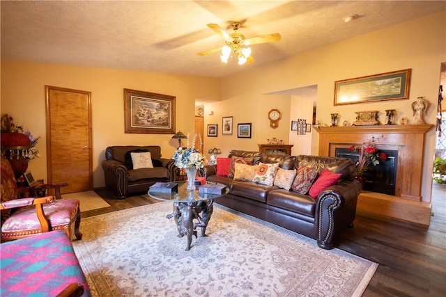 living room featuring ceiling fan, vaulted ceiling, a textured ceiling, and hardwood / wood-style floors