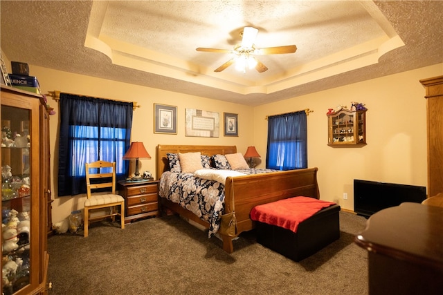 bedroom featuring a tray ceiling, carpet flooring, ceiling fan, and a textured ceiling