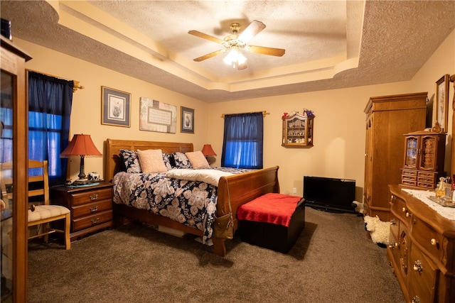 bedroom featuring a tray ceiling, ceiling fan, dark colored carpet, and a textured ceiling