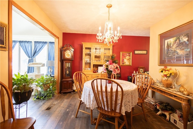 dining space featuring dark wood-type flooring and a notable chandelier