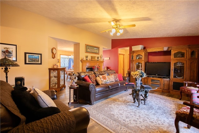 living room featuring hardwood / wood-style floors, vaulted ceiling, ceiling fan, and a textured ceiling