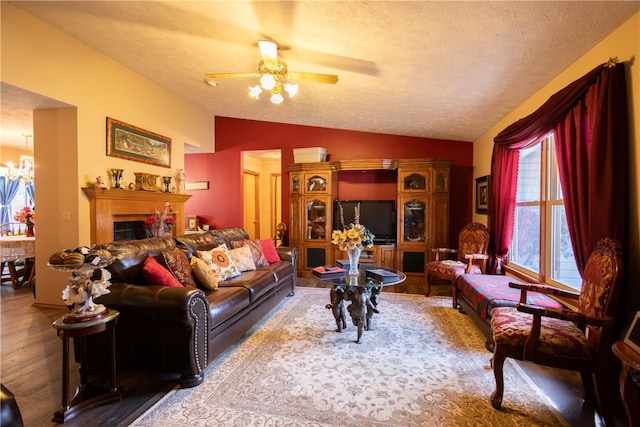 living room with a textured ceiling, ceiling fan with notable chandelier, lofted ceiling, and wood-type flooring