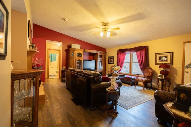 living room featuring ceiling fan, vaulted ceiling, a textured ceiling, and hardwood / wood-style flooring