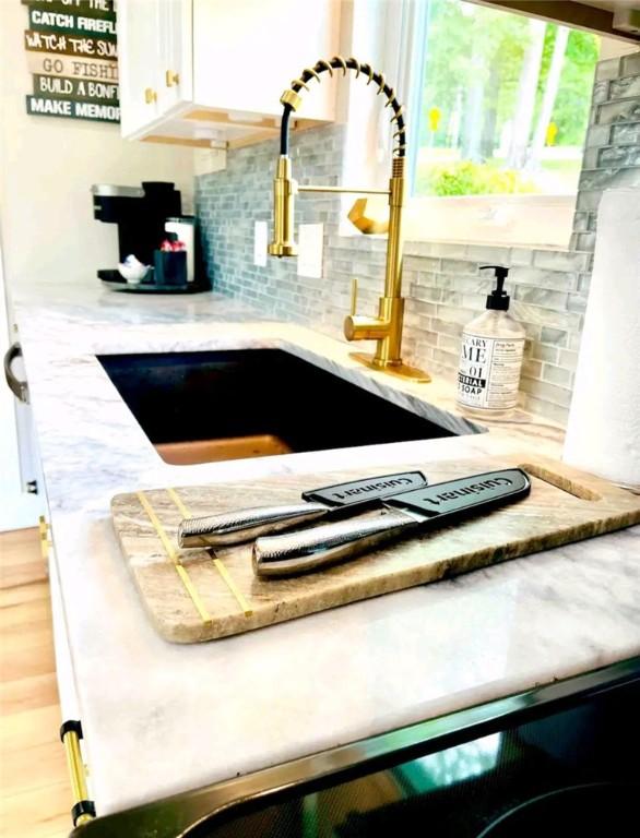 details with white cabinetry, a sink, and decorative backsplash