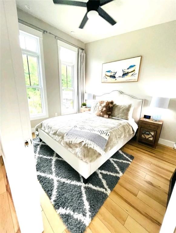 bedroom featuring ceiling fan, baseboards, and wood finished floors