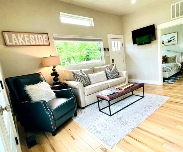 living room featuring wood finished floors, visible vents, and baseboards