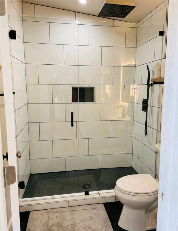 bathroom with tile patterned flooring, a shower stall, and toilet