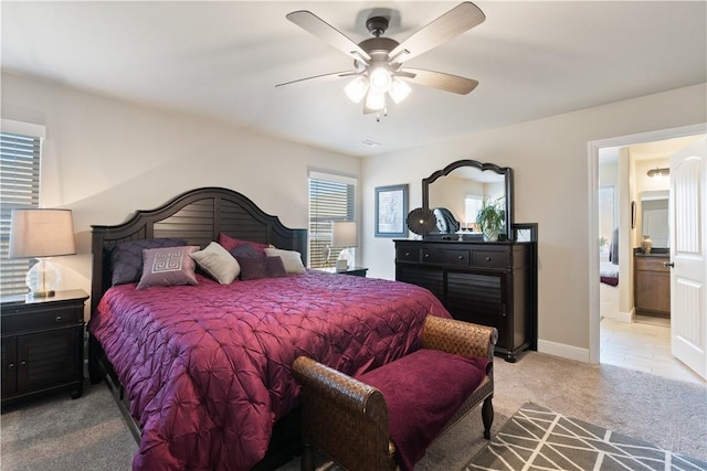 carpeted bedroom featuring ceiling fan, ensuite bath, and multiple windows