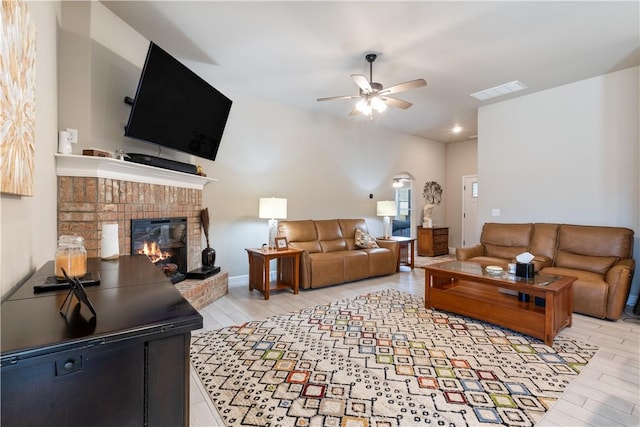 living room featuring a fireplace, light hardwood / wood-style floors, and ceiling fan