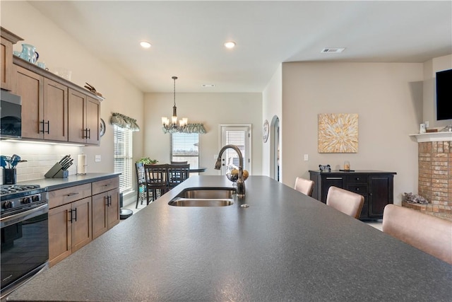 kitchen with sink, hanging light fixtures, a notable chandelier, range with gas stovetop, and decorative backsplash