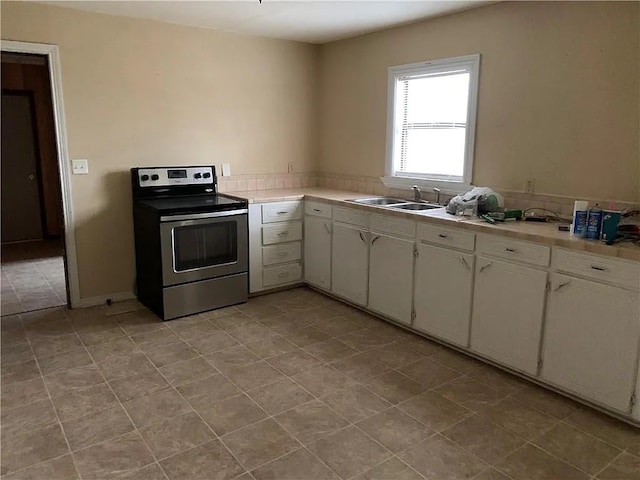 kitchen featuring sink, white cabinets, electric range, and light tile patterned flooring