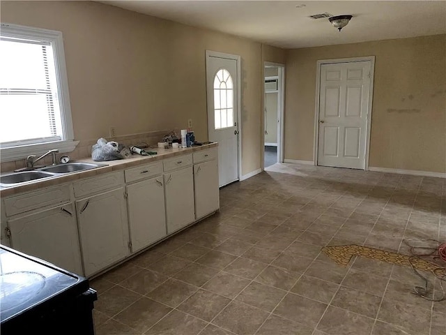 kitchen featuring light tile patterned flooring, sink, a wall mounted air conditioner, and white cabinets