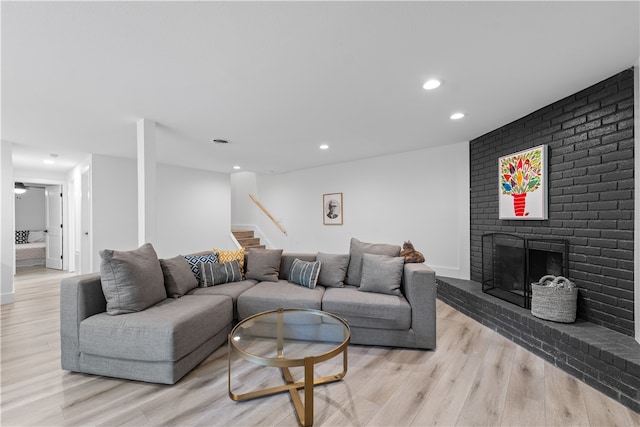 living room featuring brick wall, light wood-type flooring, and a brick fireplace