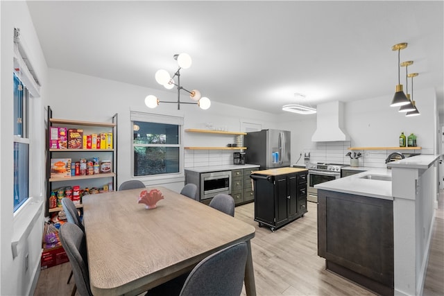 kitchen featuring sink, custom range hood, appliances with stainless steel finishes, decorative backsplash, and light hardwood / wood-style floors