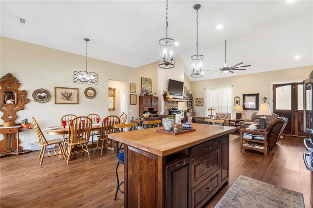 kitchen featuring dark hardwood / wood-style floors, pendant lighting, a kitchen island, ceiling fan with notable chandelier, and butcher block counters