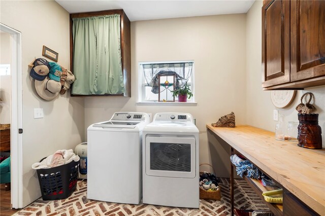 clothes washing area featuring washing machine and dryer and cabinets