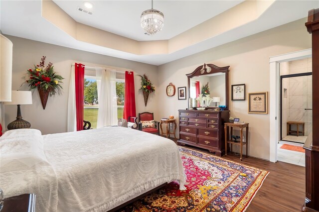 bedroom featuring a tray ceiling, a chandelier, and wood-type flooring