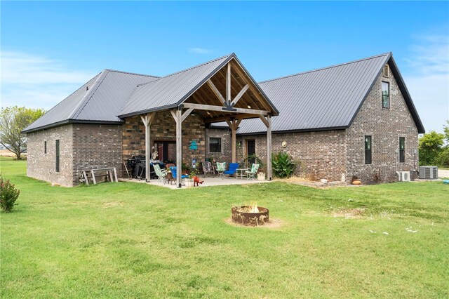 back of house with an outdoor fire pit, central AC, a lawn, and a patio