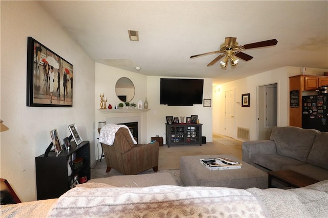 carpeted living area with ceiling fan, a glass covered fireplace, and visible vents