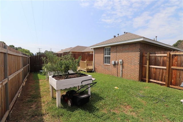 view of yard featuring a deck, a fenced backyard, and a vegetable garden