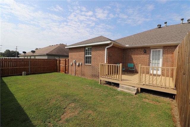 back of house with a shingled roof, a lawn, a fenced backyard, a deck, and brick siding