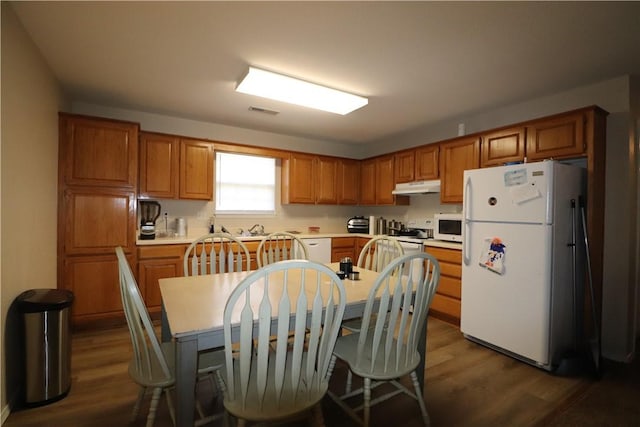 kitchen featuring white appliances, brown cabinets, and under cabinet range hood