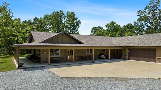 view of front of house featuring a porch, an attached garage, brick siding, driveway, and board and batten siding