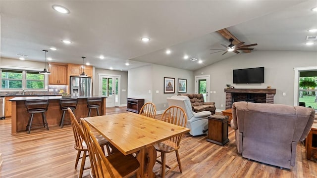 dining space featuring lofted ceiling, recessed lighting, a brick fireplace, and light wood-style floors