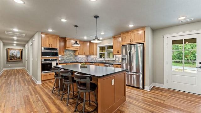 kitchen featuring visible vents, appliances with stainless steel finishes, light wood finished floors, dark countertops, and tasteful backsplash