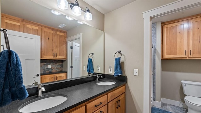 bathroom featuring visible vents, backsplash, a sink, and toilet