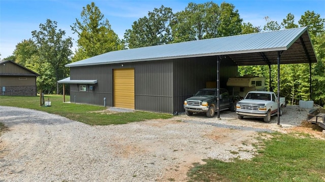 view of front of house with driveway, a detached garage, an outdoor structure, a front lawn, and a carport