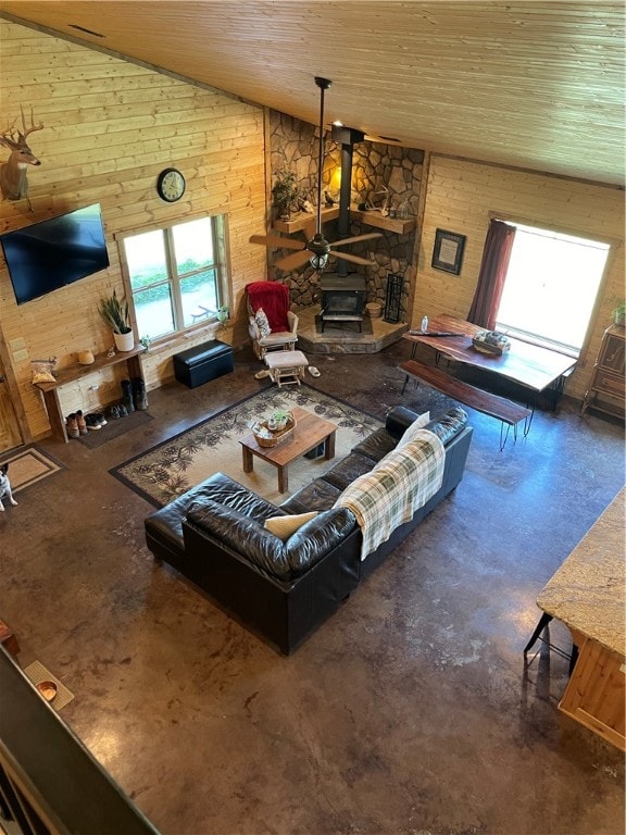 living room featuring wood ceiling, concrete floors, wood walls, and a wood stove