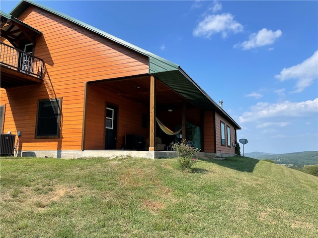 rear view of house featuring a balcony, a lawn, and cooling unit