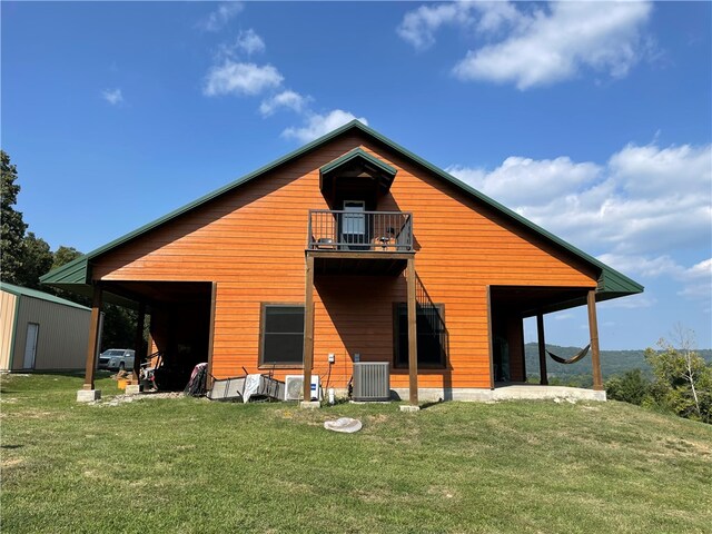 back of property featuring a balcony, central air condition unit, and a yard